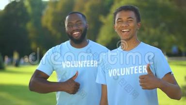 两个快乐的美国男人穿着志愿者T恤衫，竖起大拇指，<strong>无私</strong>地帮助